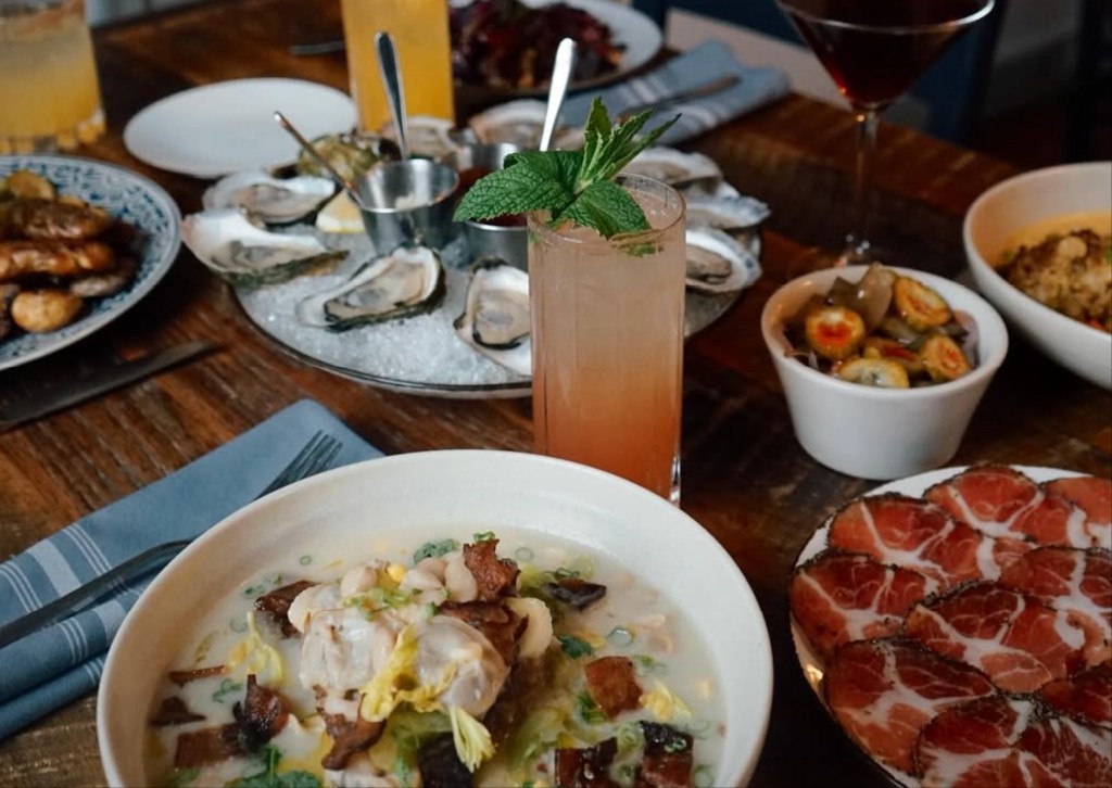 Table spread of oysters, charcuterie, and cocktails